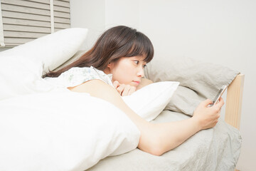 寝る前に携帯を使う若い女性