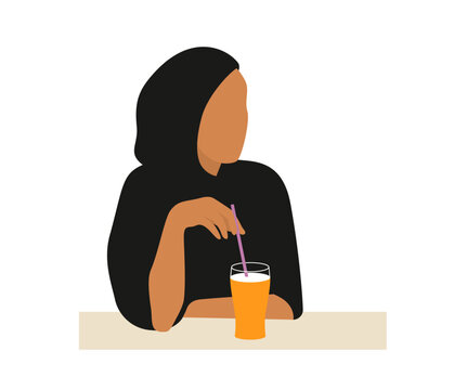 Portrait of a young Muslim woman sitting at a table and drinking orange juice