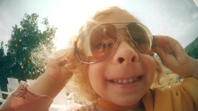 Fisheye portrait of a funny cheerful smiling girl wearing big sunglasses. Summer vacation concept