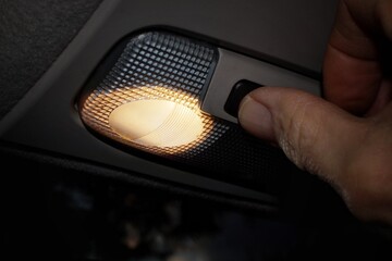 Turning on the lamp located under the ceiling of the car illuminating its interior.