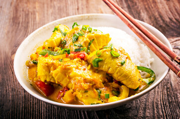 Traditional Thai fish curry with fish, vegetable and rice in spicy sauce served as close-up in design bowl