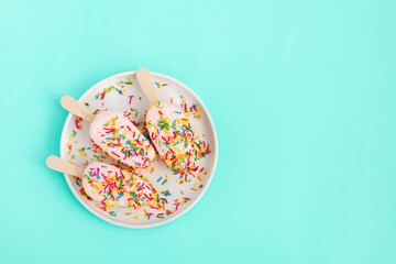 Bright and colorful flat lay of pink strawberry Popsicle ice cream on blue background. Healthy summer food concept. Top view of popsicle with sprinkles, overhead