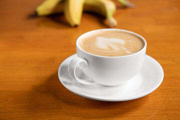 Coffee with banana milk on a wooden table
