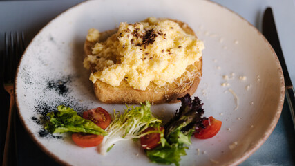 Delicious and beautiful breakfast. Toast with scramble on top, sprinkled with spices and flax seeds.