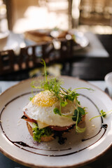 Salmon on a pillow of tomato on toast, and a poached egg on top, garnished with black sesame, spirulina and microgreens