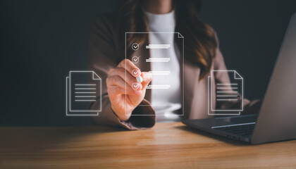 Businesswoman working on laptop with electronics document icons by virtual notebook screen using a stylus pen checking list on a digital tablet. E-document management Paperless workplace concept.