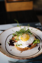 Delicious breakfast sandwich with salad, cheese and fried egg on top