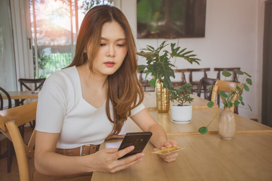 Young woman using credit card and mobile phone for online shopping in cafe, coworking space or coffee shop. Technology money wallet, online payment concept, credit card mockup. Safe mobile banking