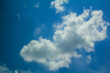 Looking from the car window, a big white fluffy cloud in the blue sky. For background, wallpaper, digital artwork use and etc..