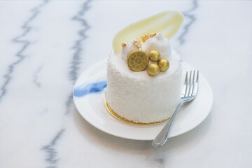 Coconut cake decorated with golden balls, golden leaf, biscuits and white chocolate