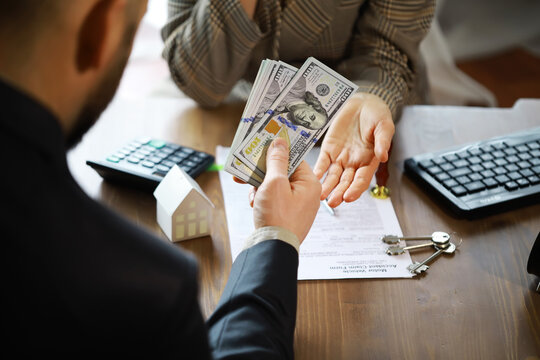 European Businesswoman Working In Real Estate Company. She Is Giving Cash Money To Male Customer.