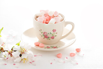 Coffee cup with a delicate floral pattern. Marshmallows and sweets in the shape of a heart. Almond flowers. Valentine's day. March 8, women's day