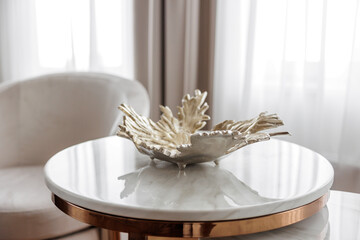 Abstract gold vase on the table in the interior of the house. Luxury bedroom in a house with modern interior design, coffee table, gold decor. 