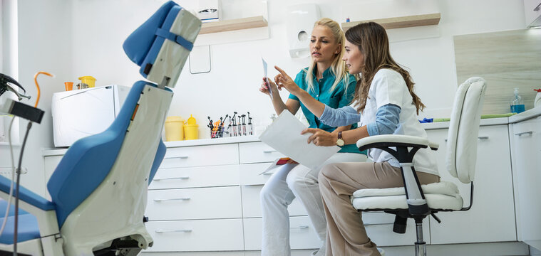 Two female dentists discuss and examine the x-ray image of the patient's teeth.	
