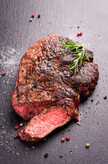 Barbecue aged angus rib eye beef steak with salt and pepper served as close-up on a black design...
