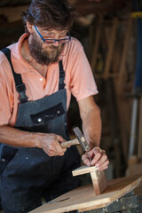 Carpenter using working tools while working on a wood in carpentry workshop