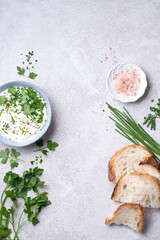 Ingredients for simple green  butter board. Butter with fresh herbs: wild onion, parsley, rosemary and pink salt on a wooden board, gray stone background, rustic style. Simple and healthy snacks - 578044284