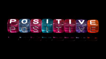 word "positive" written in colorful cubes isolated on dark background. concept of positive thinking in life. inscription in colorful blocks. symbols that contain motivational messages