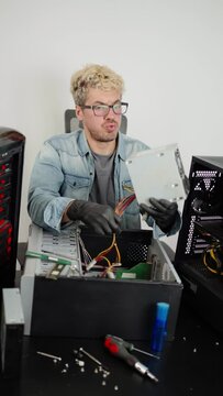 Young man looking exhausted at work while repairing computer. White background