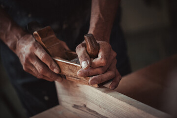 Carpenter using working tools while working on a wood in carpentry workshop