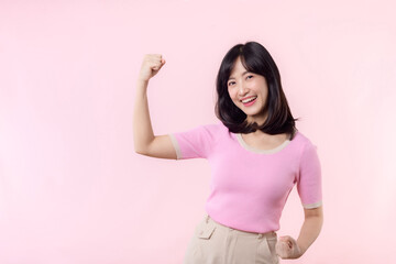 Portrait young asian woman proud and confident showing strong muscle strength arms flexed posing,...