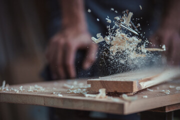 Carpenter using working tools while working on a wood in carpentry workshop - obrazy, fototapety, plakaty