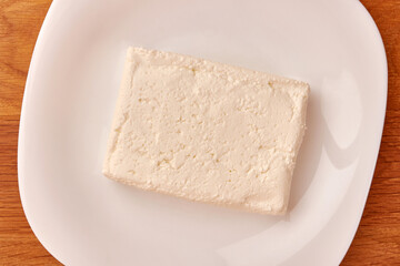 A slice of sour milk cheese on a white plate.