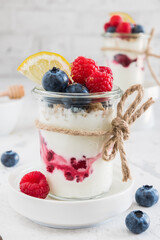 Yogurt with berries and cereals in a glass on white background, vertical