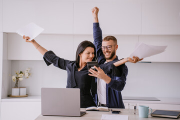 Excited caucasian couple after calculate their year earnings, celebrating successful business at...