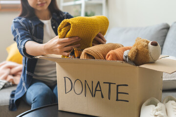 Recycling, Donation for poor, hand asian young woman, girl packing object at home, putting on stuff into donate box with second hand clothes, charity helping and needy people. Reuse recycle, moving.