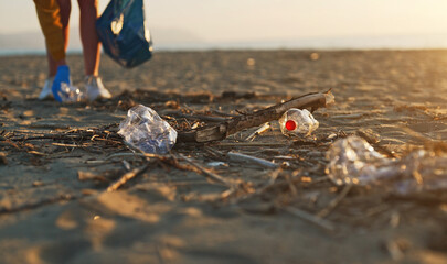 Woman volunteer collects garbage on the beach. Environmental pollution.