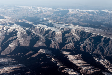 Aerial high altitude view of mountain range crossed by shadows from rising sun, Caucasus , Georgia