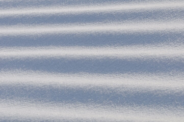 Obraz premium Snow lies in waves in a cold snowy winter, the play of light in straight lines