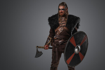 Obraz premium Shot of medieval nordic barbarian with black fur and armor holding axe.