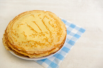 A stack of freshly baked pancakes on a blue and white napkin on the table.