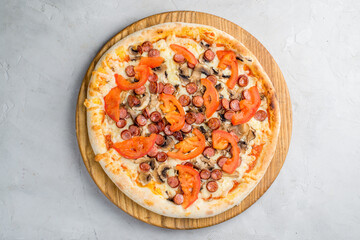 Pizza with vegetables, sausages and ham