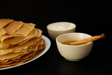 Thin pancakes with sour cream on board
