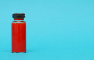 Medical ampoule with blood on a blue background.