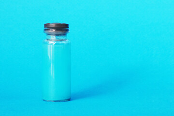 Glass ampoule with blue liquid on a blue background.