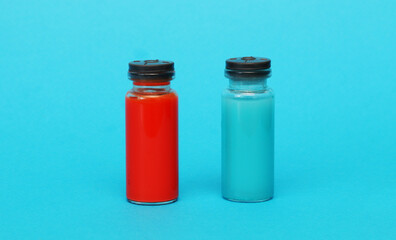 Two medical glass bottles with blue and red liquid.
