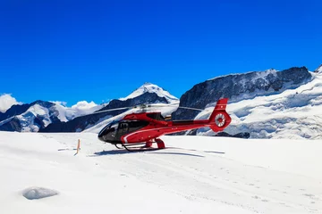 Tuinposter Red helicopter landed at Jungfrau mountain in Bernese Oberland, Switzerland © olyasolodenko