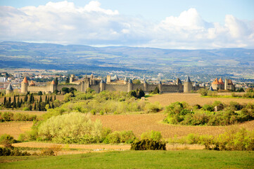 View of medieval town of Carcassonne through vines and fields. Languedoc, Occitania, France. Travel background.