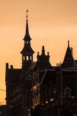 Obraz premium A pink and orange sunset behind a beautiful building in Amsterdam, Netherlands