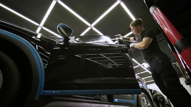 Man covering car with vinyl polyurethane tape. Films for the car. Sticker protective film on the car