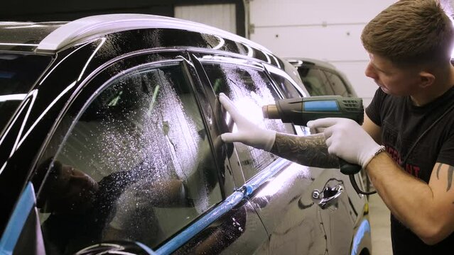 Man covering car with vinyl polyurethane tape. Films for the car. Sticker protective film on the car