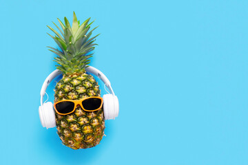Ripe pineapple with sunglasses and headphones on blue background