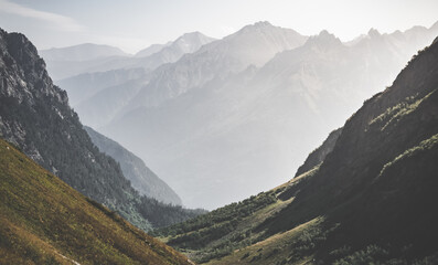 Mountain valley with slopes and rocky cliffs, stone mountain ranges with vegetation, against the background of a cloudy forest sky, mountain summer landscape