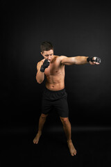 Boxer throwing a punch. Photo of muscular man isolated on black background. Strength and motivation.