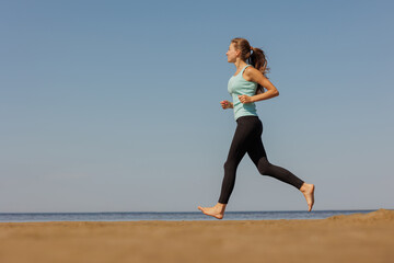 Fototapeta premium jogging, sporty woman runs in morning on seashore. fitness millennial female trains for marathon, healthy lifestyle, love for her body, mental and physical condition, sportswear, champion