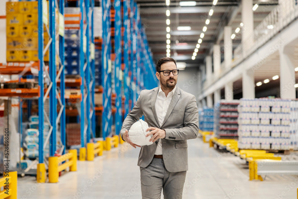 Sticker A businessman walking trough the big distribution center and checking on goods.